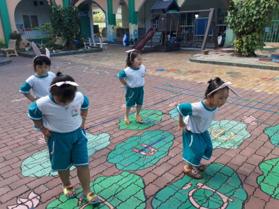 Các bé đang chơi nhảy qua những chiếc lá sen ngoài sân trường